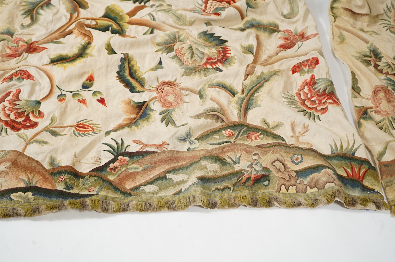 Six 20th century crewel work ‘Tree of Life’ cream linen curtains. Worked at the base in coloured wools depicting a pastoral scene of a shepherd playing a flute amongst sheep, deer, squirrels and flowers with a dog chasin